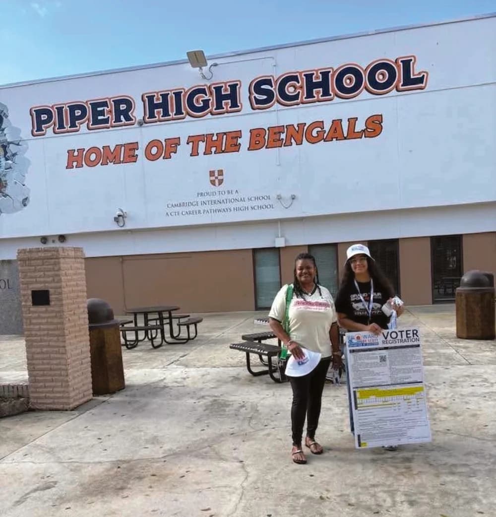 Dr. Mary Smith beside a voter registration display outside Piper High School